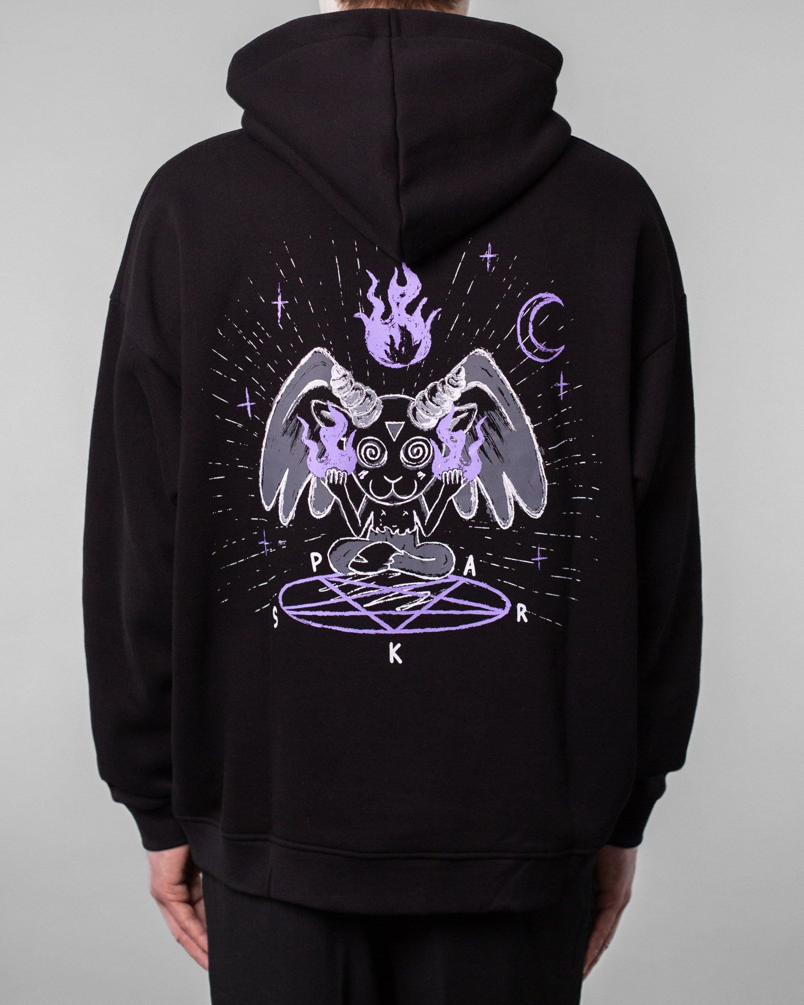 Rückansicht desselben schwarzen Hoodies. Das großflächige Rückenmotiv zeigt eine mystische Cartoonfigur mit Hörnern, Flügeln und Flammen in den Händen, die mit gekreuzten Beinen über einem lilafarbenen Pentagramm sitzt. Darüber schwebt eine lila Flamme, umgeben von Mondsichel, Sternen und Lichtlinien. Die Buchstaben „S“, „P“, „A“, „R“, „K“ sind rund um das Pentagramm angeordnet.