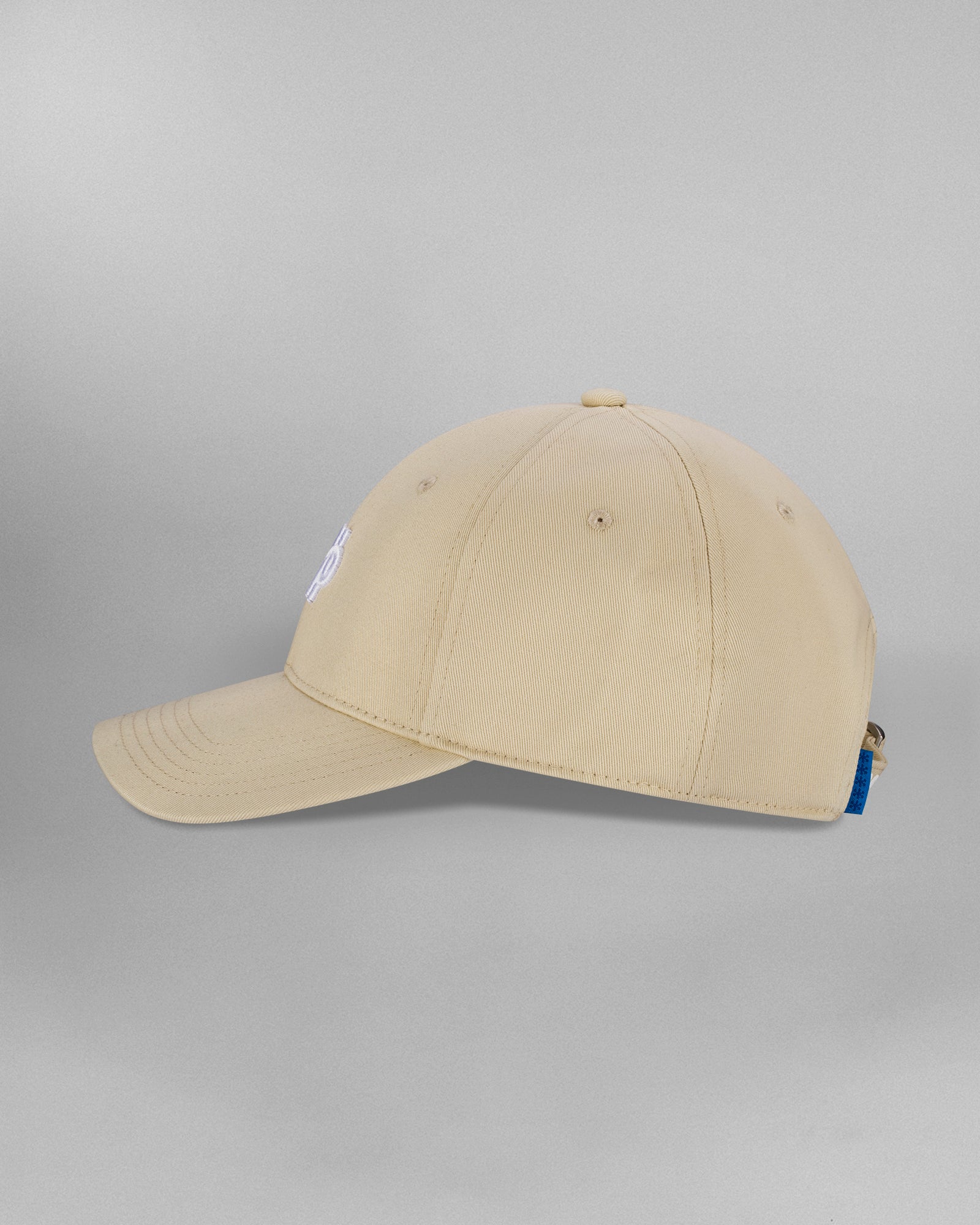 Frontalansicht einer beigefarbenen Cap mit mittig platziertem weißen Sticklogo aus grafischen Linien- und Bogenelementen. Der Schirm ist leicht nach unten gebogen.