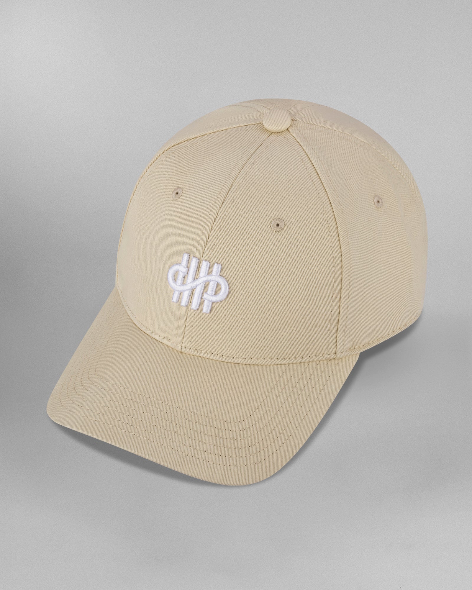 Linke Seitenansicht der beigefarbenen Cap mit zentralem Sticklogo auf der Front. Der verstellbare Riemen mit blauer Einfassung ist dezent am Hinterkopf zu sehen.