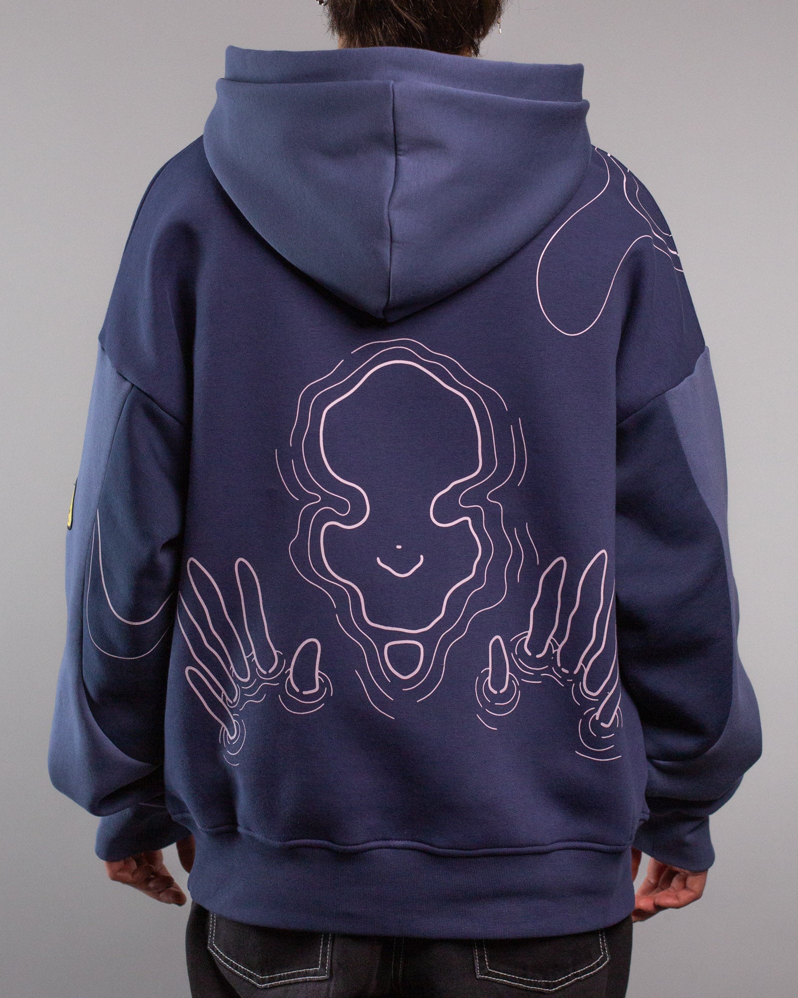 Rückansicht des Hoodies mit großem, mittig platziertem Linienmotiv in Rosa. Die Illustration zeigt ein stilisiertes, lächelndes Gesicht in Wasserlinienoptik, flankiert von beiden Händen mit ausgestreckten Fingern, die ebenfalls aus geschwungenen Linien bestehen.