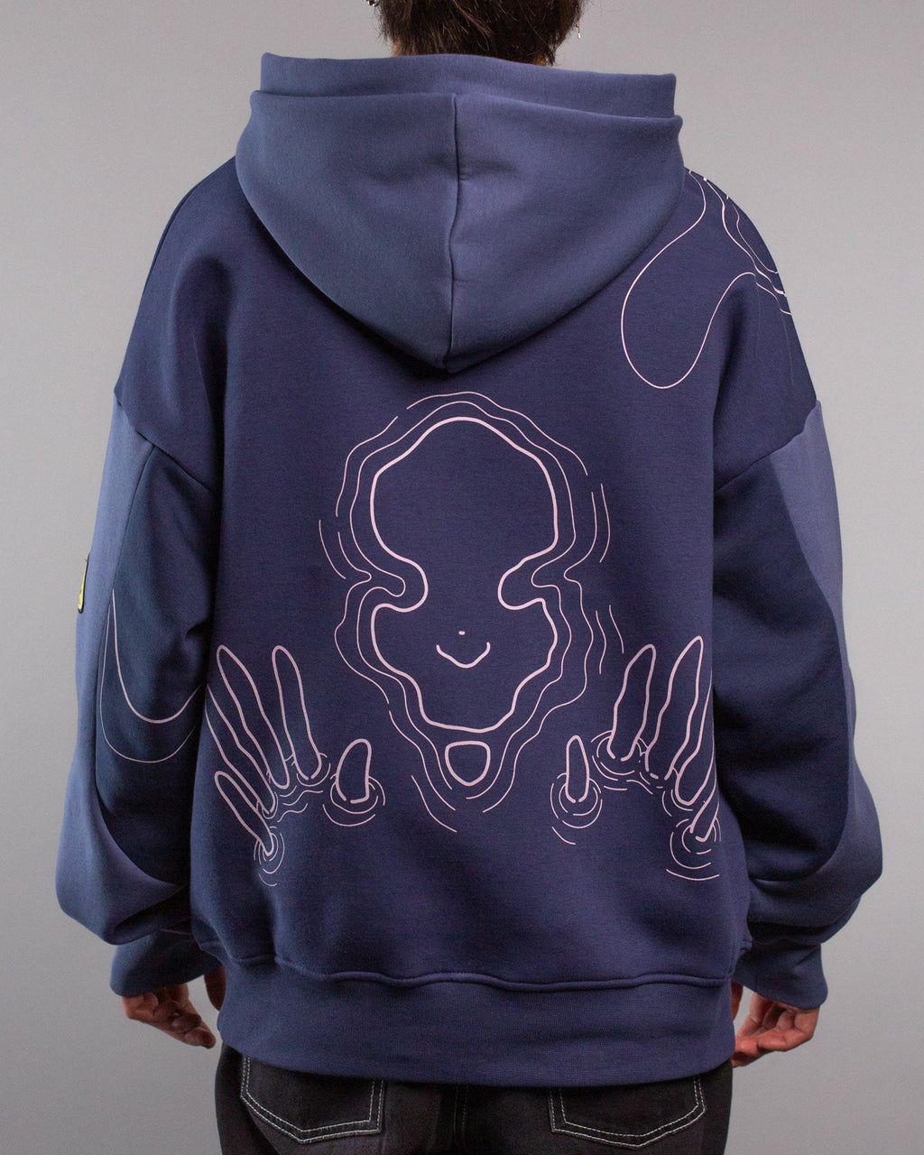 Rückansicht des Hoodies mit großem, mittig platziertem Linienmotiv in Rosa. Die Illustration zeigt ein stilisiertes, lächelndes Gesicht in Wasserlinienoptik, flankiert von beiden Händen mit ausgestreckten Fingern, die ebenfalls aus geschwungenen Linien bestehen.