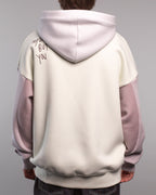 Rückansicht des Hoodies mit Schriftzug „ANYONE BUT YOU“ in dunkelvioletter Stickerei auf der linken Schulter. Die Kapuze ist fliederfarben, Rumpf und Rücken des Hoodies sind cremefarben gehalten.