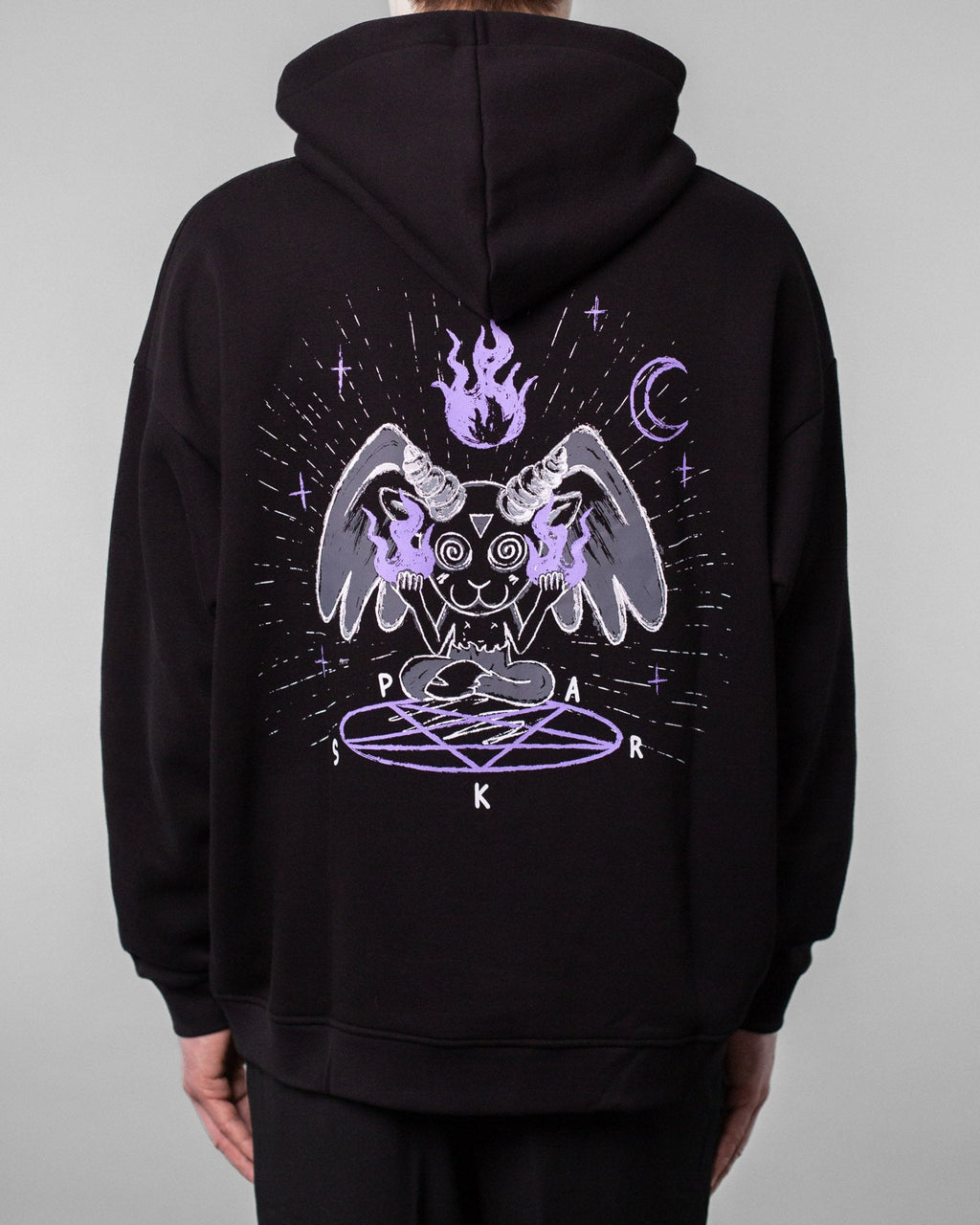 Rückansicht desselben schwarzen Hoodies. Das großflächige Rückenmotiv zeigt eine mystische Cartoonfigur mit Hörnern, Flügeln und Flammen in den Händen, die mit gekreuzten Beinen über einem lilafarbenen Pentagramm sitzt. Darüber schwebt eine lila Flamme, umgeben von Mondsichel, Sternen und Lichtlinien. Die Buchstaben „S“, „P“, „A“, „R“, „K“ sind rund um das Pentagramm angeordnet.