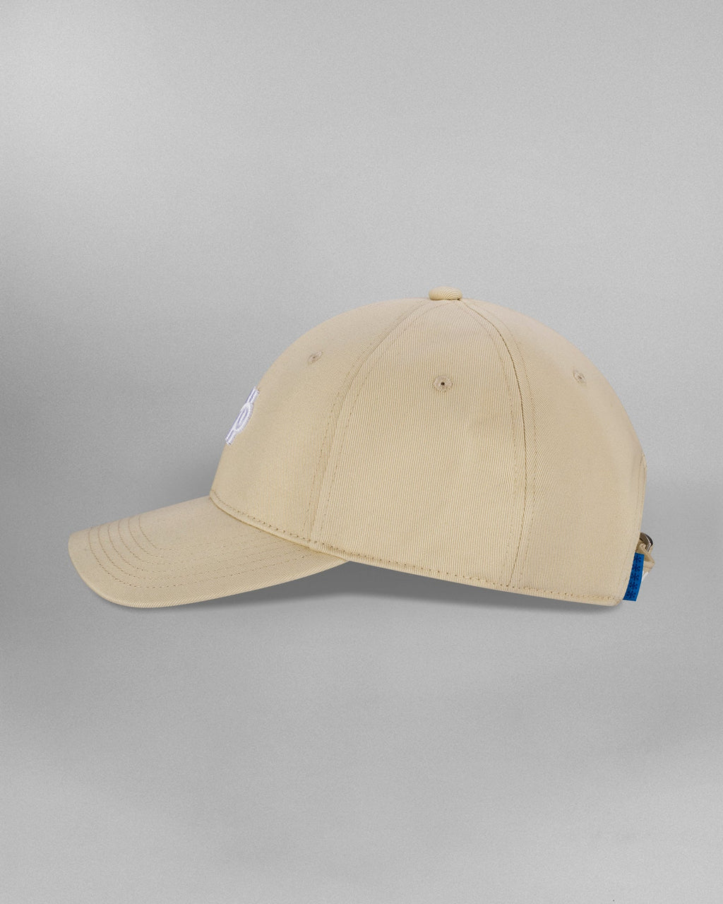 Frontalansicht einer beigefarbenen Cap mit mittig platziertem weißen Sticklogo aus grafischen Linien- und Bogenelementen. Der Schirm ist leicht nach unten gebogen.