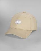 Beigefarbene Baseballcap in schräger Frontansicht, mit geschwungenem weißem Sticklogo aus vertikalen Linien und Schleifenform auf der Vorderseite. Die Kappe zeigt sichtbare Ziernähte und Luftlöcher.
