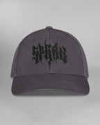 Linke Seitenansicht der Cap. Am hinteren Panel ist ein schwarzes Unendlichkeitssymbol mit einem angedeuteten Totenkopf eingestickt. Die geschwungene Form erstreckt sich bis zum Mittelpanel.