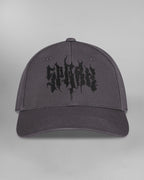 Linke Seitenansicht der Cap. Am hinteren Panel ist ein schwarzes Unendlichkeitssymbol mit einem angedeuteten Totenkopf eingestickt. Die geschwungene Form erstreckt sich bis zum Mittelpanel.