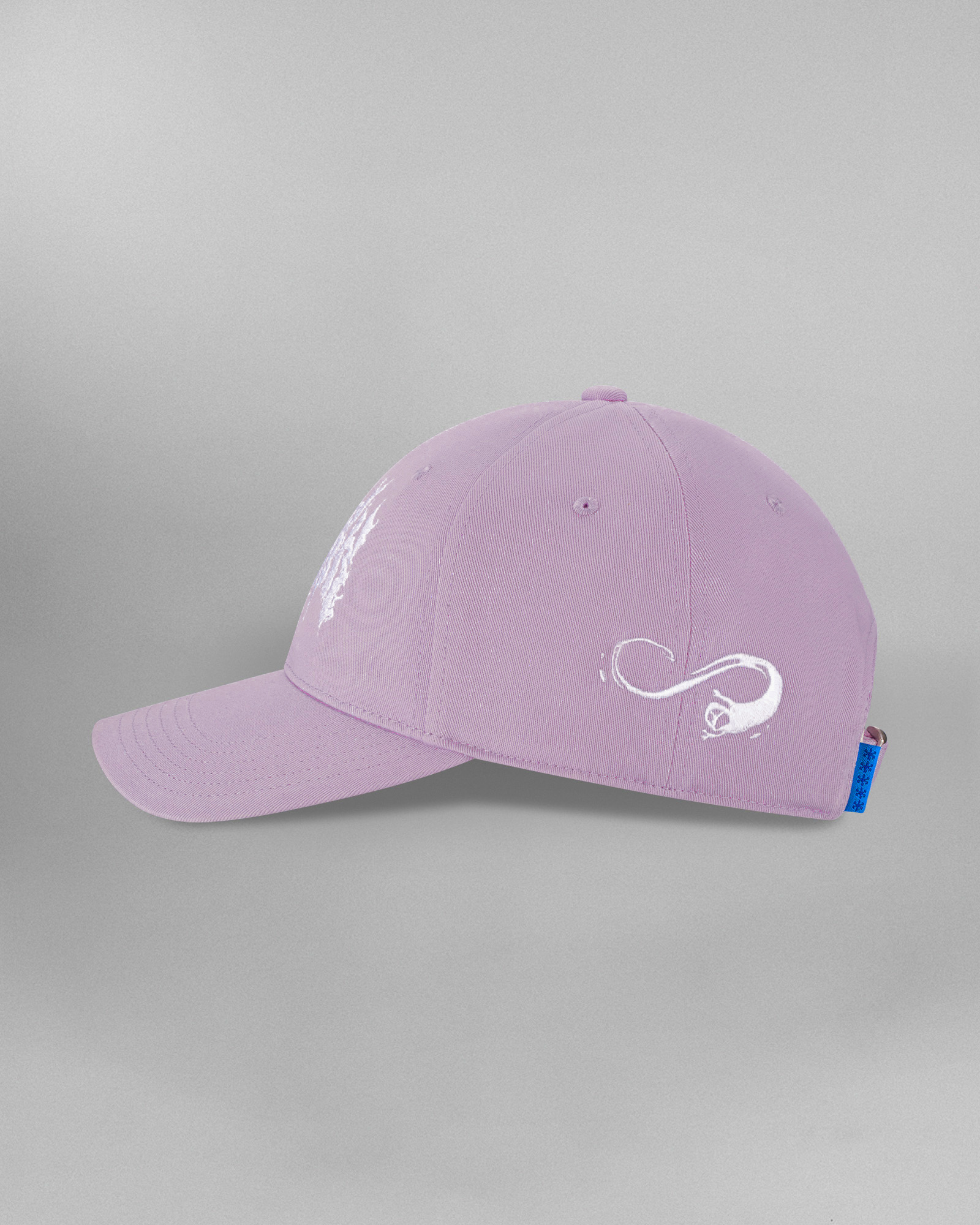 Rückansicht der fliederfarbenen Cap mit verstellbarem Riemen und Metallschnalle. Der Riemen zeigt die weiße Aufschrift „SP*RK“ sowie ein blaues Etikett. Links ist ein geschwungenes weißes Symbol, rechts eine Reihe stilisierter Sarg-Icons in Weiß aufgestickt.