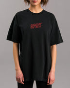 Frontalansicht einer Person, die ein locker geschnittenes schwarzes T-Shirt mit rotem „SPRK“-Schriftzug auf der Brust trägt.