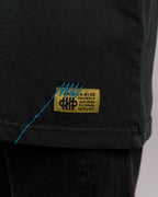 Nahaufnahme des unteren Saums des T-Shirts mit eingenähtem gelben Weblabel mit blauer Ziernaht und gelbem Textfeld „SP*RK.4.0-22“, darunter weitere Zeichenkombinationen.


