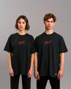 Zwei Personen in identischem schwarzen T-Shirt mit rotem „SPRK“-Frontprint, stehend in neutraler Studio-Umgebung.