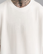 Nahaufnahme der weißen „SPARK“-Stickerei auf der Brust des weißen T-Shirts, Ton-in-Ton gestaltet.