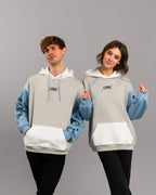 Zwei Personen stehen nebeneinander und tragen identische Hoodies mit hellem Grundton, weißen Kapuzen und hellblauen Ärmeln. Auf der Brust befindet sich ein kleiner „SPRK“-Schriftzug, auf den Ärmeln verschiedene Symbole und der Schriftzug „THINK“. Beide Personen lächeln und posieren spielerisch.