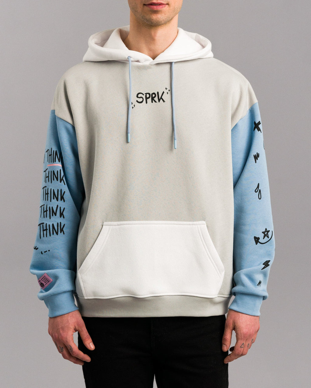 Frontalansicht des Hoodies mit Fokus auf die Vorderseite. Zu sehen sind die weiße Kängurutasche, hellblaue Ärmel mit schwarzem Druck und der zentrale schwarze „SPRK“-Schriftzug auf Brusthöhe.