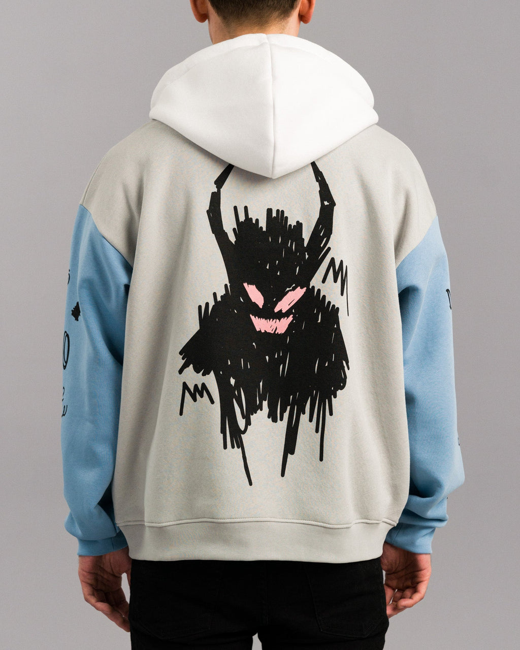 Rückansicht des Hoodies mit Fokus auf die große Illustration. Das Motiv zeigt eine krakelig-schwarze, dämonenhafte Figur mit rosa Augen und breitem Mund, gedruckt mittig auf den Rückenbereich.