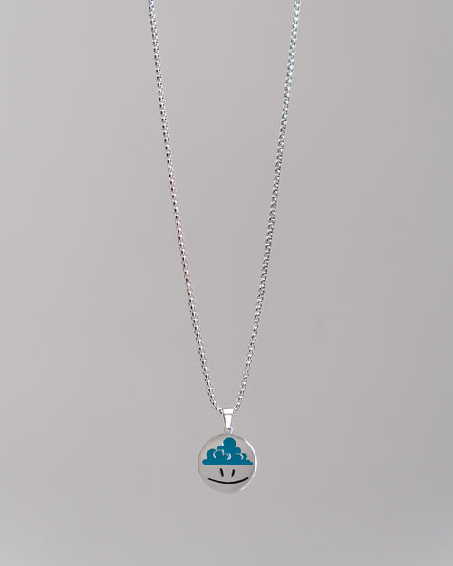 Silberne Gliederkette mit rundem Anhänger; der Anhänger zeigt ein grafisches Wolkensymbol mit zwei schwarzen Augen auf glatter Oberfläche.