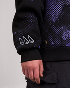 Nahaufnahme des rechten Ärmels eines schwarzen Hoodies mit violettem Punktmuster. Auf dem Ärmel sind drei weiße, stilisierte Tropfen mit lächelnden Gesichtern aufgedruckt.