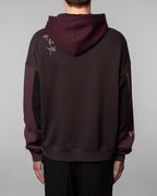 Rückansicht des Hoodies mit einfarbig dunklem Rückenbereich. Auf der Schulterpartie ist in heller, handschriftlicher Schrift der Text „ANYONE BUT YOU“ in drei Zeilen aufgestickt. Die Kapuze ist weinrot.