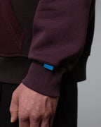 Detailansicht des linken Ärmelbündchens mit hellblauem Labelpatch und feiner Naht am Übergang zum Rumpfbereich.