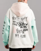 Rückansicht des Hoodies mit mehrfach aufgedrucktem schwarzen Text „PARTY IN MY HEAD“ in verschiedenen Schriftarten. Rosa Kritzelgrafiken wie Planetenring und Fragezeichen ergänzen das Design.