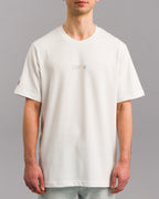 Weißes Unisex-T-Shirt mit farbiger „SP/RK“-Stickerei mittig auf der Brust. Linker Ärmel mit pinkfarbenem Labelaufnäher. Das Shirt ist locker geschnitten und hat einen Rundhalsausschnitt.