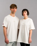 Zwei Personen tragen das gleiche weiße T-Shirt mit „SP/RK“-Stickerei auf der Brust. Beide Shirts zeigen das pinke Ärmel-Label und sind locker geschnitten.