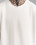 Nahaufnahme der weißen „SPARK“-Stickerei auf der Brust des weißen T-Shirts, Ton-in-Ton gestaltet.