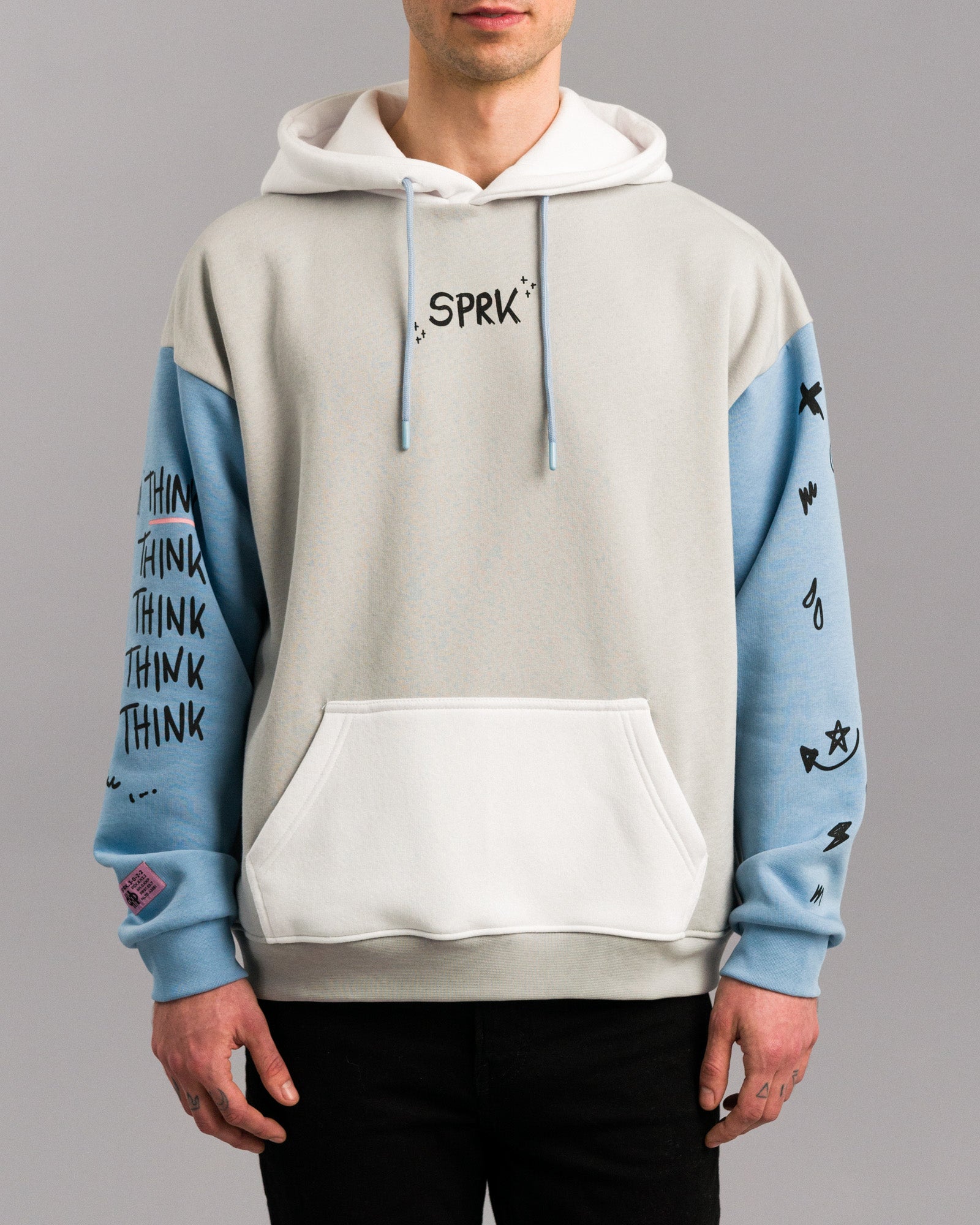 Frontalansicht des Hoodies mit Fokus auf die Vorderseite. Zu sehen sind die weiße Kängurutasche, hellblaue Ärmel mit schwarzem Druck und der zentrale schwarze „SPRK“-Schriftzug auf Brusthöhe.