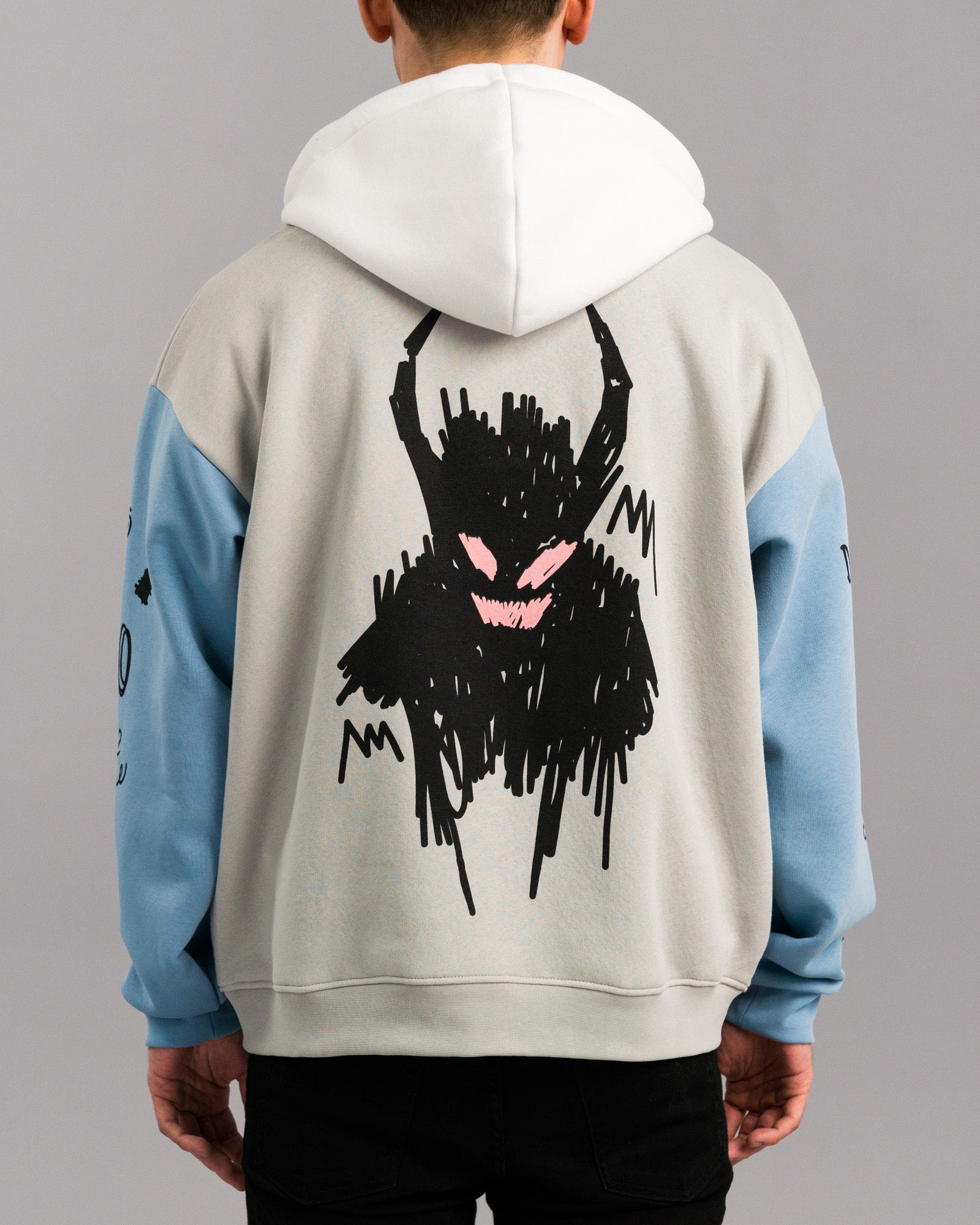 Rückansicht des Hoodies mit Fokus auf die große Illustration. Das Motiv zeigt eine krakelig-schwarze, dämonenhafte Figur mit rosa Augen und breitem Mund, gedruckt mittig auf den Rückenbereich.