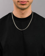 Nahaufnahme einer silberfarbenen Gliederkette in mittelbreitem Design, getragen über einem schwarzen T-Shirt. Die Kette liegt locker um den Hals und hebt sich kontrastreich vom dunklen Hintergrund ab.