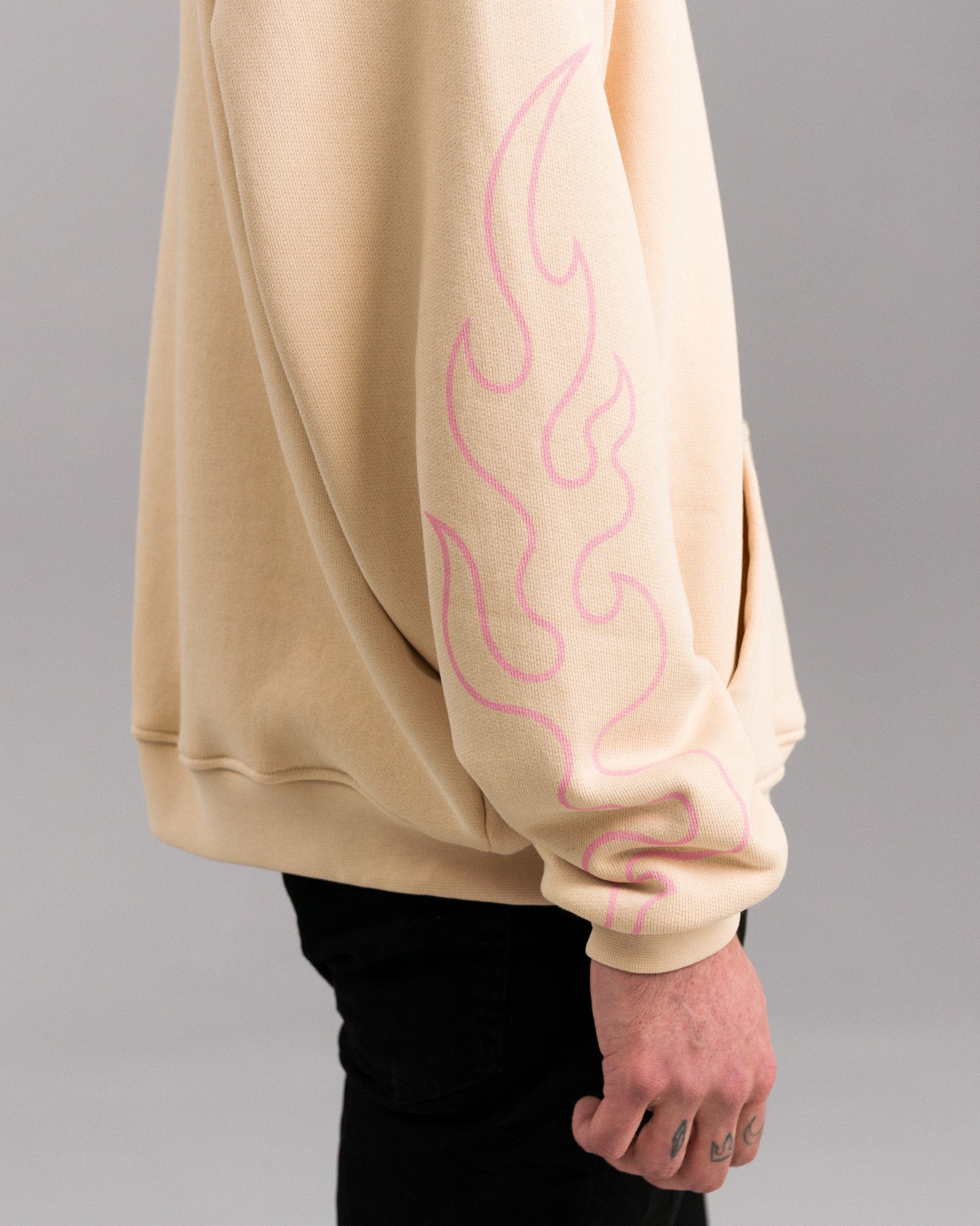 Seitenansicht des linken Ärmels mit rosa Flammenmotiv in grafischem Stil, das sich vertikal entlang des Unterarms zieht.

