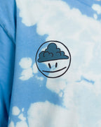 Detailansicht des Smiley-Prints auf dem T-Shirt mit Batikmuster. Das Motiv zeigt ein rundes Gesicht mit ernster Miene und einer dunklen Wolke im oberen Bereich des Kopfes.